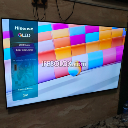A Hisense QLED 75 inch television mounted on a beige wall, displaying a colorful interface with a blue sidebar and a vibrant grid of pastel blocks on the screen. A watermark reading 'IFESOLOX.