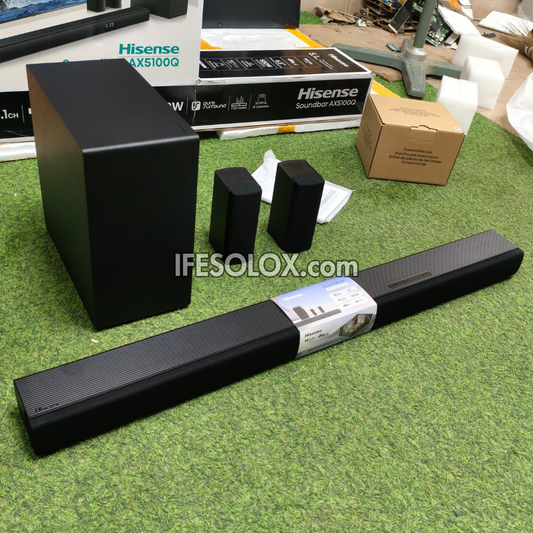 Hisense 5.1 soundbar speaker system with a subwoofer, two satellite speakers, and original packaging boxes arranged on artificial green turf.