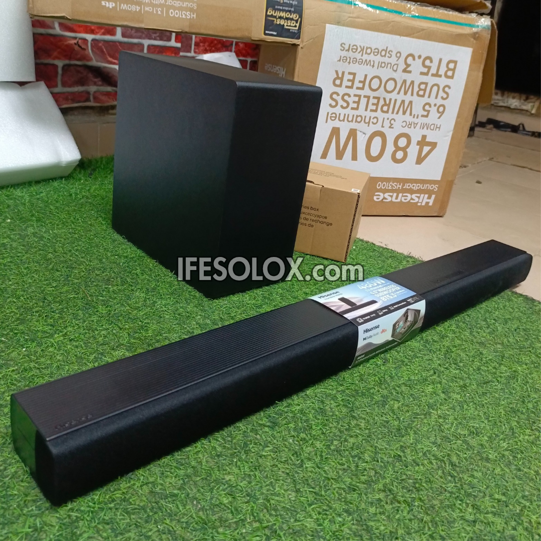 Hisense HS3100 Black soundbar and subwoofer on a grassy surface with cardboard boxes in the background.