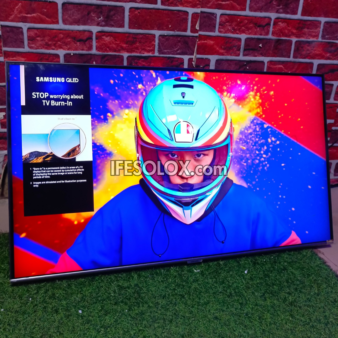 Samsung QLED TV displaying a colorful helmet graphic with a brick wall background