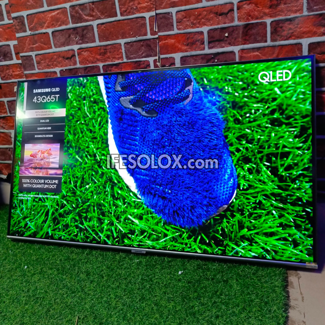 Samsung QLED TV displaying a blue shoe on grass with a brick wall background