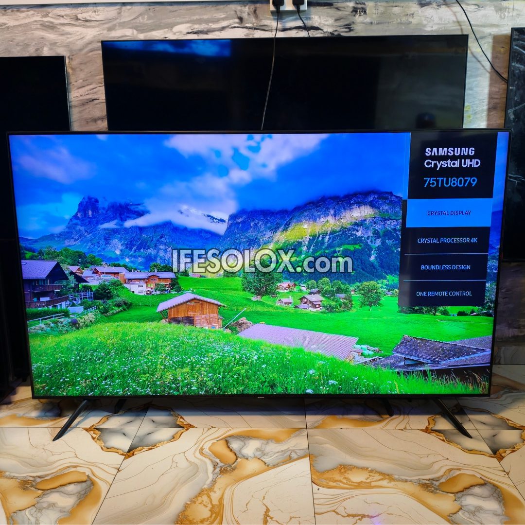 Samsung Crystal UHD 75TU8079 television displaying a colorful mountain landscape, set on a marble-patterned floor in a showroom.