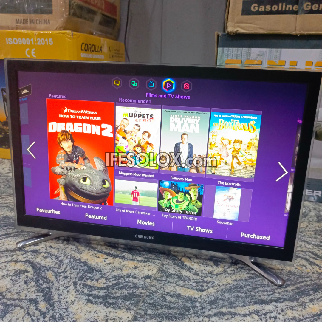 Samsung 22 inch Smart TV displaying a streaming platform interface with various movies and shows on a textured surface.