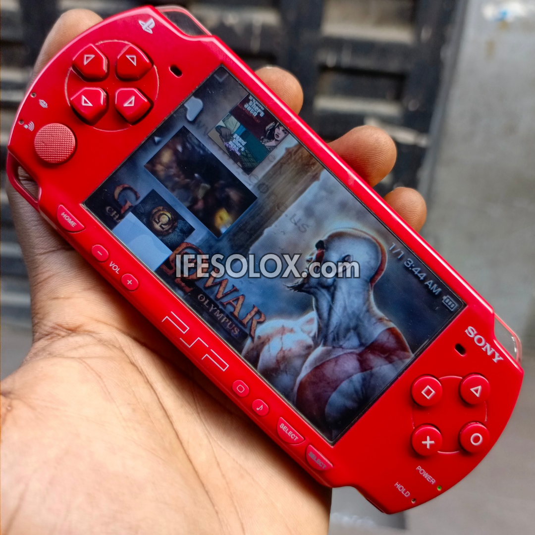 Red Sony PSP held in a hand playing God of War
