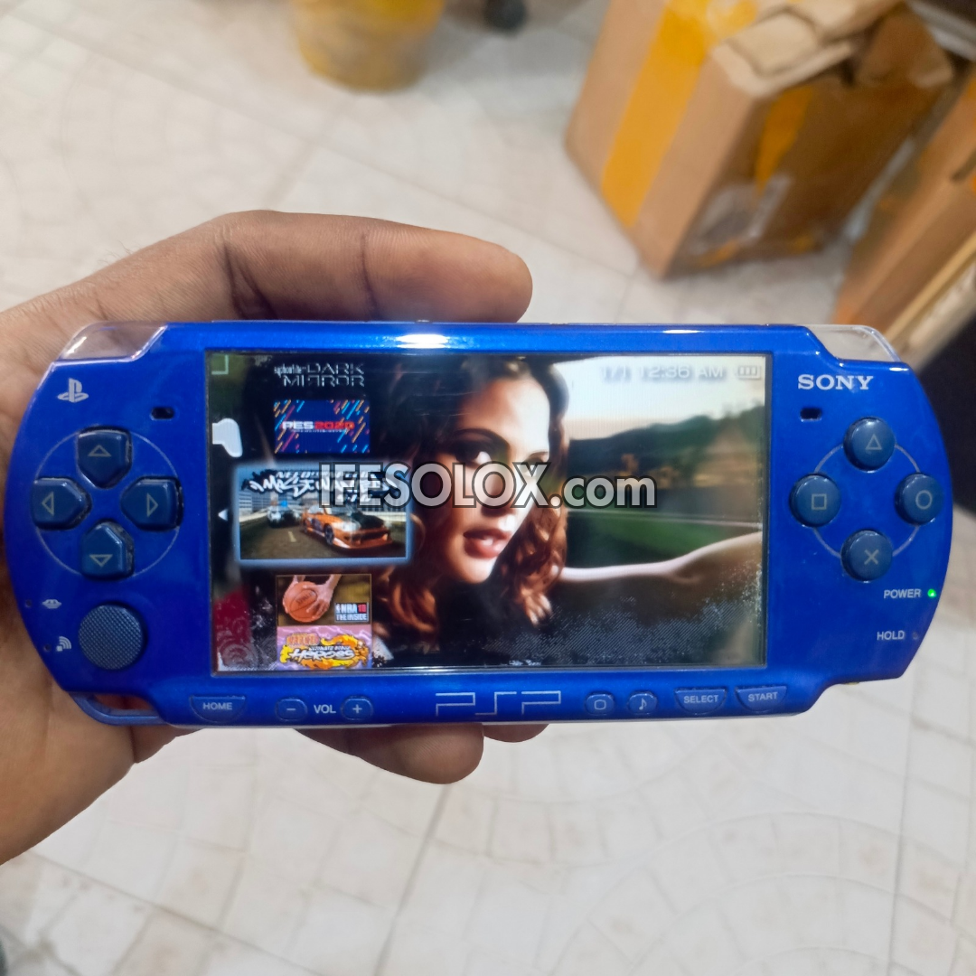 Blue Sony handheld gaming console with a screen displaying graphics, held by a person.
