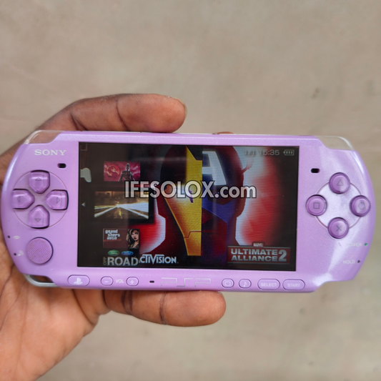 A lavender purple Sony PSP handheld gaming console held in a hand, displaying a game screen with a prominent 'IFESOLOX.com' watermark overlay.