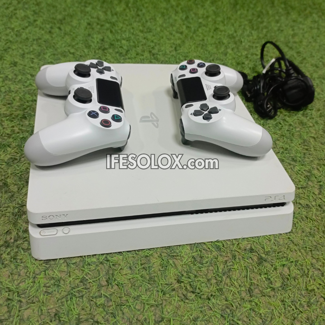 White PS4 gaming console with two controllers on a grassy background